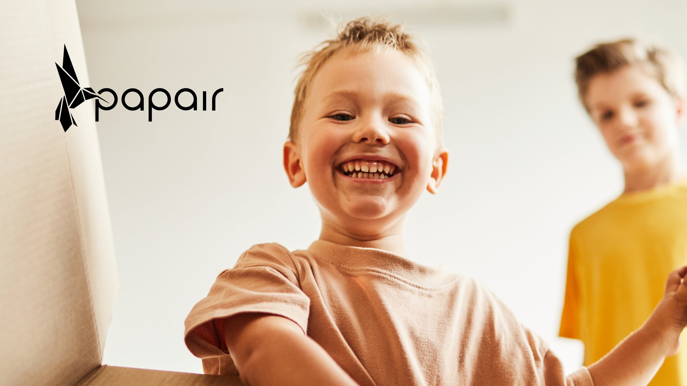das Markenlogo der Marke Papair auf einem Bild von einem kleinen Jungen, der in einen Karton schaut